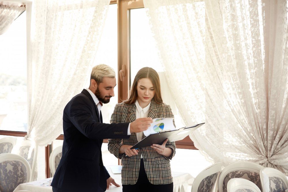 A man and woman in business attire reviewing a document, symbolizing professional wedding planning services in New Jersey.