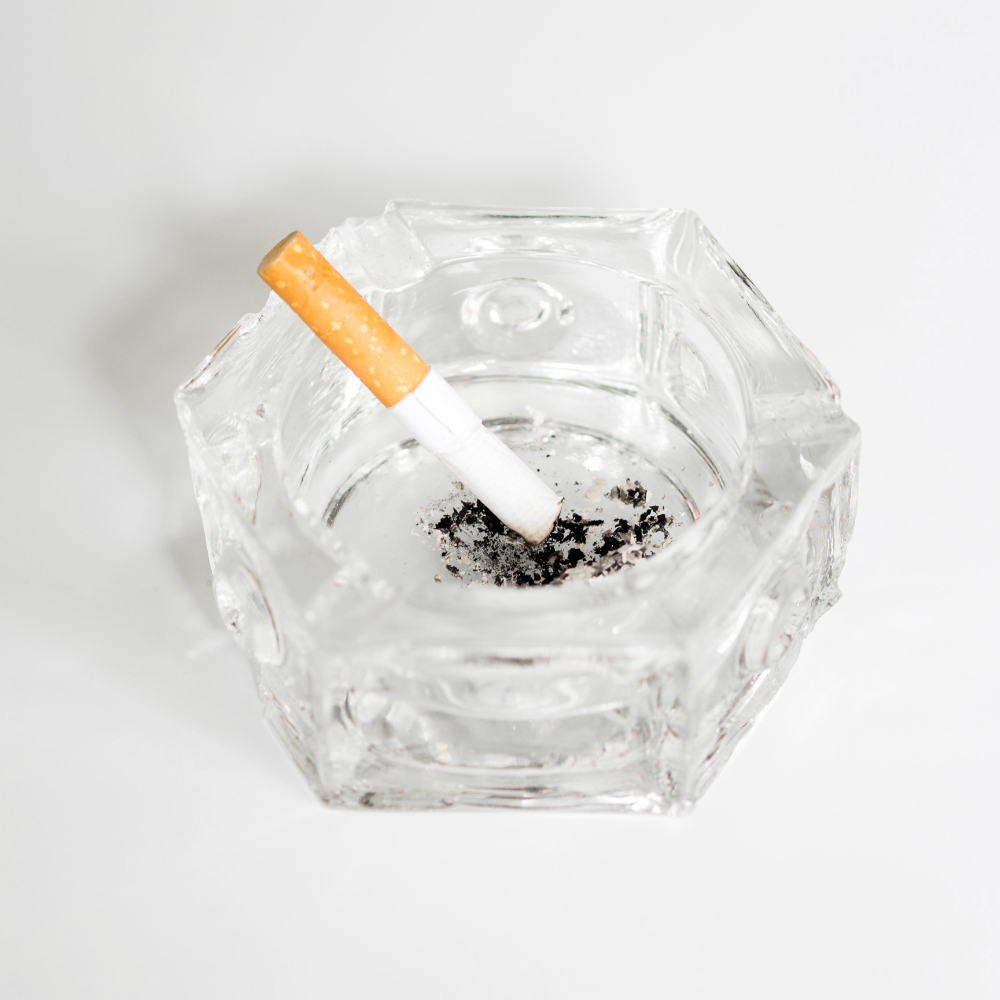 A cigarette positioned in a glass ashtray, illustrating a serene scene within a collection of smoke storage trays.