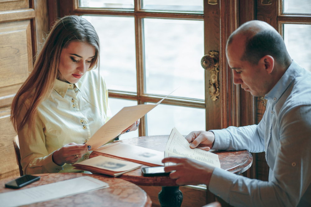 A man and woman, both Psychic Advisors, sitting at a table, focused on reviewing important documents.